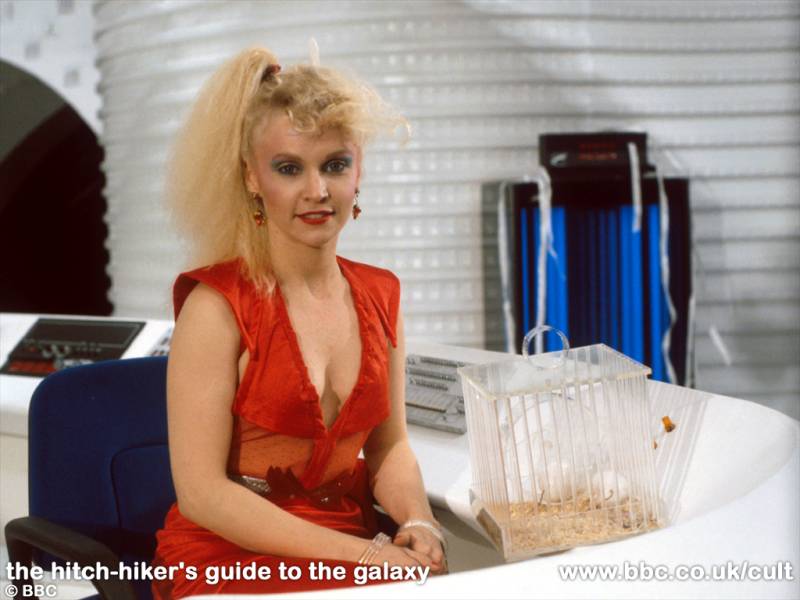 Trillian seated with a plastic mouse cage. From Hitchhikers Guide To The Galaxy.