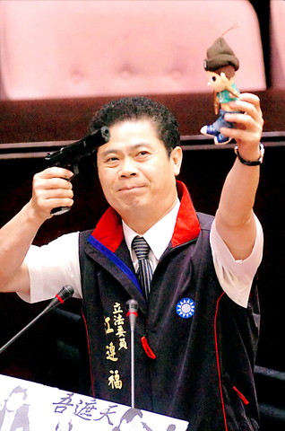 Taiwanese KMT legislator Chiang Lien-fu aims a gun at a toy doll of Taiwanese president Chen Shui-bian in Taiwan's parliament