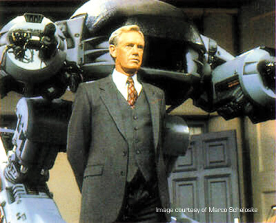 Dick Jones standing in front of the ED-209 robot in Robocop