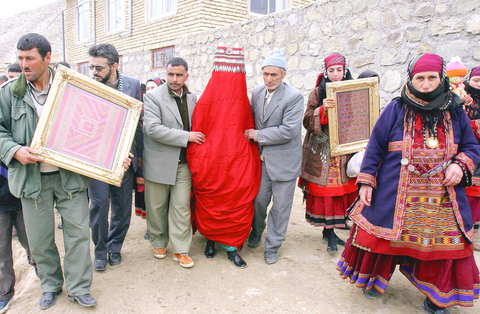 Iranian wedding with woman completely covered with a red bag, covering her eyes as well. She walks with the guidance of two men on each side of her.