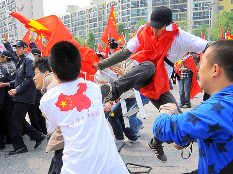 A pro-CCP Chinese thug kicks an unarmed South Korean protester in the back during a rally against the Chinese Olympic torch relay.