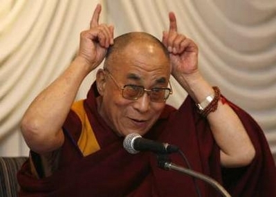 The Dalai Lama playfully makes devil horns on his head for the camera