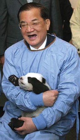 Former KMT chairman Lien Chan in a protective blue animal care suit, beaming with a baby panda in his lap.