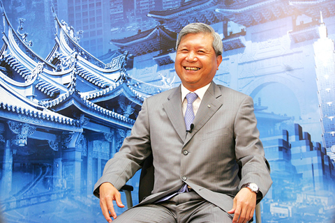 Acer chairman J.T. Wang sits in a gray suit in front of a painting of a Chinese temple.