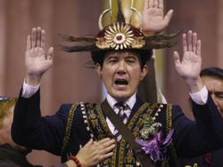 Ma Ying-jeou raises both hands while wearing aboriginal clothing over his dark suit and tie.