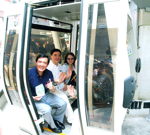 Ma Ying-jeou sitting next to other passengers while he gives a thumbs up sign. 
