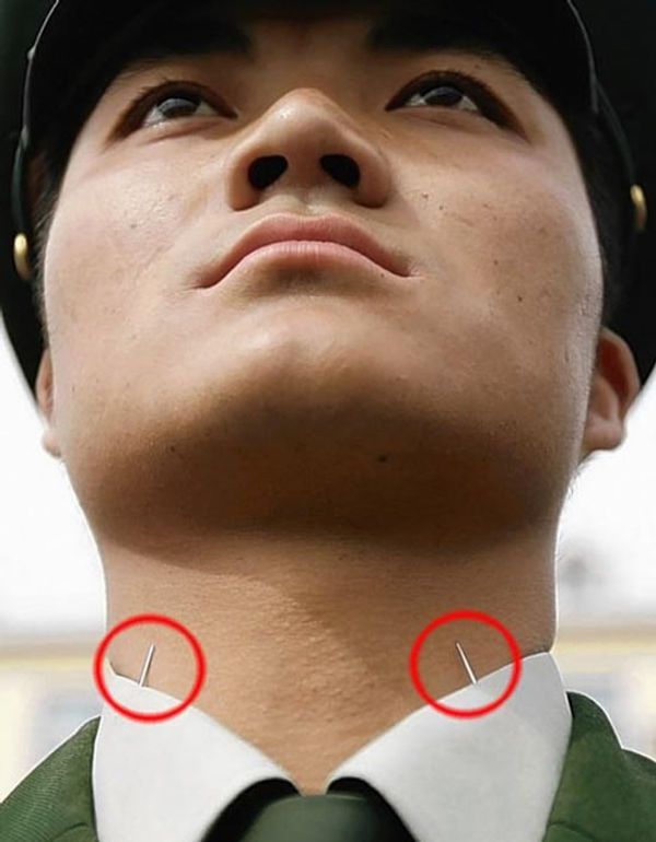 People's Liberation Army soldier standing at attention, head not drooping down because of needles in his collar.