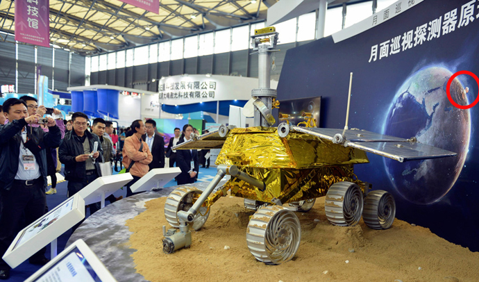 China Threatens Europe With Nuclear Destruction. A mock moon-rover is displayed at a trade show, with a stock poster featuring a nuclear strike on Europe behind it.