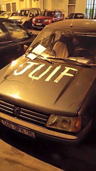 A Parisian car with the word, 'Juif' (Jew) spray-painted on the hood.