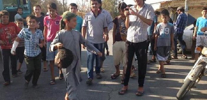 Muslim child in ISIS territory carries a decapitated head after an execution.